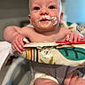 baby, infant, child, portrait, smiling, messy_face, frosting, cake, food, high_chair, sitting, indoor, close_up, blue_eyes, hands, colorful, celebration, birthday, playful, photography