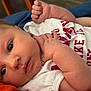 Alexis joined the competition — help win amazing prizes! baby, infant, close_up, face, hand, white_shirt, red_text, blue_cushion, orange_surface, skin, newborn, expression, portrait, young_child, lying_down, cute, sleepy, indoors, person, human