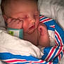 baby, newborn, sleeping, blanket, hospital_wristband, wrapped, infant, cute, peaceful, child, face, skin, hand, resting, portrait, indoors, soft, cozy, toddler, person