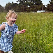 Mavis is registered to the contest to win money with this photo: child, toddler, smiling, running, outdoor, grass, wildflowers, blue_dress, boots, nature, trees, meadow, greenery, happy, sky, cloudy, field, cute, playful, person