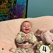 Mia is registered to the contest to win money with this photo: baby, infant, smiling, clapping_hands, floral_pajamas, pink_blanket, plush_star, plush_elephant, milestone_card, four_months, tapestry, skull_design, indoor, cute, happy, child, soft_texture, cozy, sitting, portrait