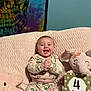 baby, infant, smiling, clapping_hands, floral_pajamas, pink_blanket, plush_star, plush_elephant, milestone_card, four_months, tapestry, skull_design, indoor, cute, happy, child, soft_texture, cozy, sitting, portrait