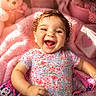 baby, smiling, infant, floral_clothing, pink_blanket, teddy_bear, soft_toys, cute, joyful, happy, child, portrait, indoors, cozy, colorful, cute_decor, baby_girl, close_up, playful, warm_lighting