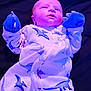 Kolten joined the competition — help win amazing prizes! baby, newborn, infant, onesie, dinosaur_pattern, mittens, lying_down, purple_lighting, clothing, child, cute, portrait, indoor, young, person, sleepwear, soft, face, expression, cozy