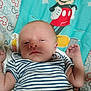 baby, infant, striped_clothing, mickey_mouse, blanket, cartoon, sleepy, lying_down, child, cute, toddler, face, head, arm, hand, pattern, colorful, smiling, portrait, indoors