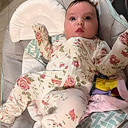 Rebecca is registered to the contest to win money with this photo: baby, infant, onesie, floral_pattern, cushion, baby_seat, blanket, indoor, floor_tile, face, person, cute, clothing, child, young, comfort, resting, expression, portrait, home