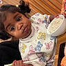 bowl, butterfly_print, child, chopsticks, clothing, cute, expression, face, food, funny_face, indoors, meal, person, pigtails, restaurant, rice, sitting, table, toddler, wooden