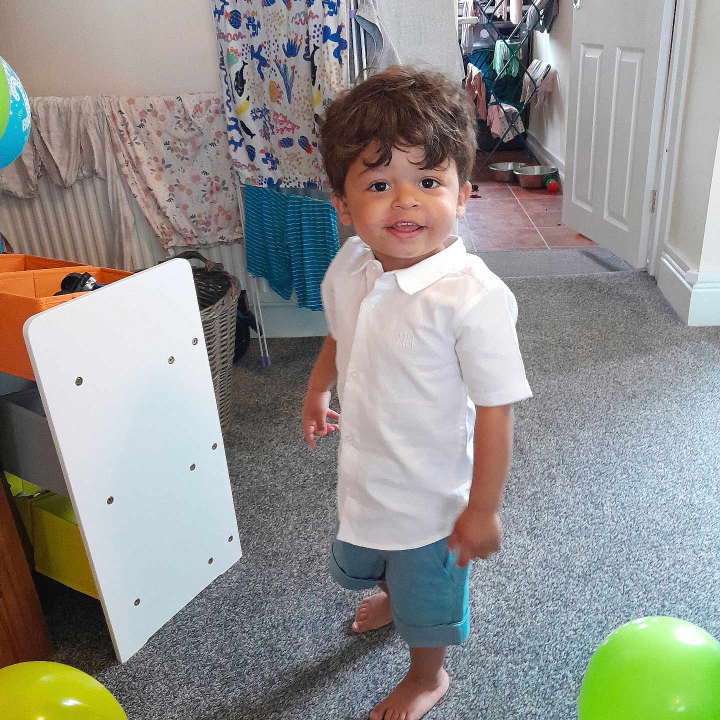 Sullivan is registered to the contest to win money with this photo: balloon, box, boy, child, clothing, dress, face, furniture, head, indoors, interiordesign, male, pants, person, photography, portrait, shorts, standing, t_shirt, wood