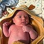 newborn, baby, towel, hooded_towel, blanket, star_pattern, infant, skin, face, hand, fist, lying_down, cute, soft_texture, indoors, resting, young_child, wrapped, cozy, sleepwear
