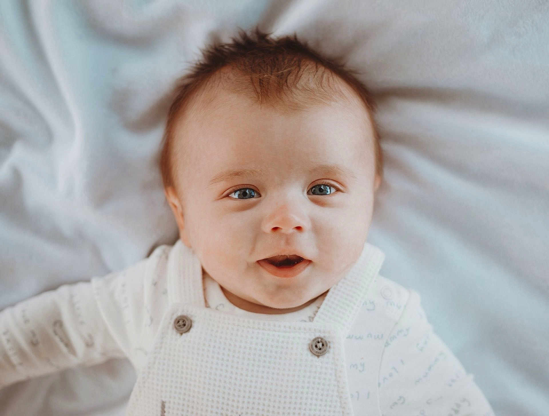River-Bleu joined the competition — help win amazing prizes! baby, infant, smiling, face, blue_eyes, white_clothing, blanket, portrait, cute, child, soft_lighting, closeup, happy, laying_down, buttoned_overalls, young, skin, head, expression, indoors