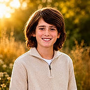Bryler joined the competition — help win amazing prizes! child, smile, outdoor, golden_hour, sunlight, nature, wildflowers, greenery, portrait, young, happy, hair, brown_hair, sweater, cozy, warm_colors, face, person, casual_clothing, natural_light