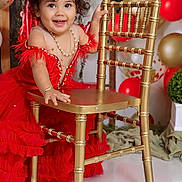 Ainhoa is registered to the contest to win money with this photo: toddler, child, red_dress, tiara, golden_chair, balloons, party, celebration, smiling, curly_hair, jewelry, necklace, bracelet, indoor, decorations, happy, portrait, festive, cute, posing