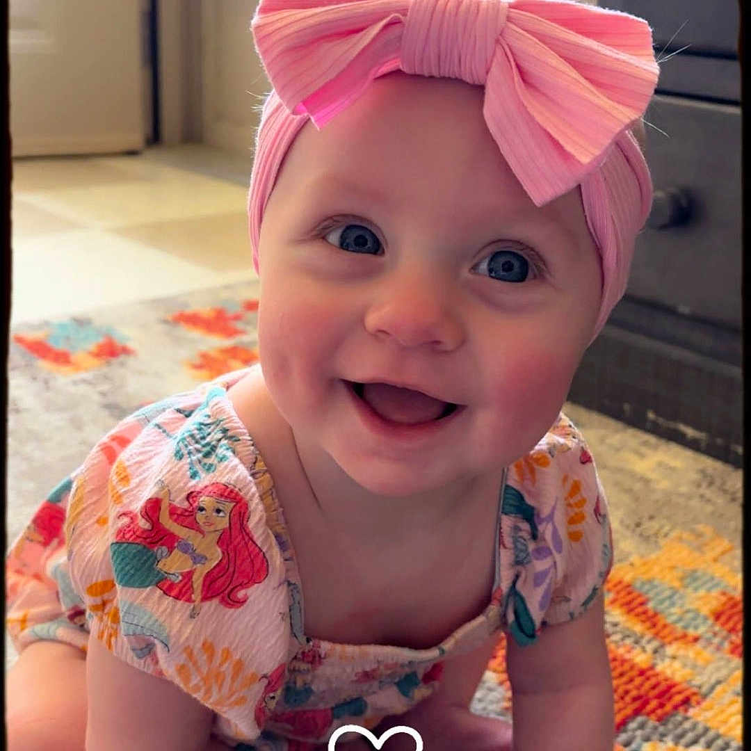 Camry is registered to the contest to win money with this photo: accessories, baby, clothing, costume, dress, face, glasses, happy, hat, head, headband, indoors, jewelry, laughing, necklace, person, photography, portrait, purple, smile