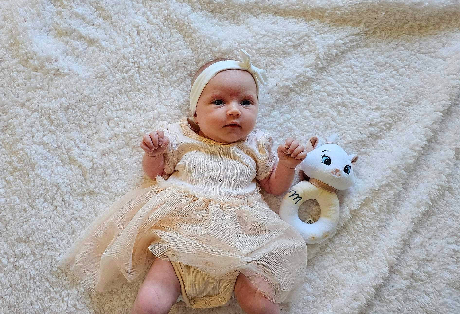 Tessa a rejoint le concours — aidez-le/la à gagner de superbes lots ! baby, baby_toddler_clothing, child, comfort, doll, dress, eye, fashion_accessory, fawn, flooring, fur, grass, happy, head, linens, person, skin, textile, toddler, toy
