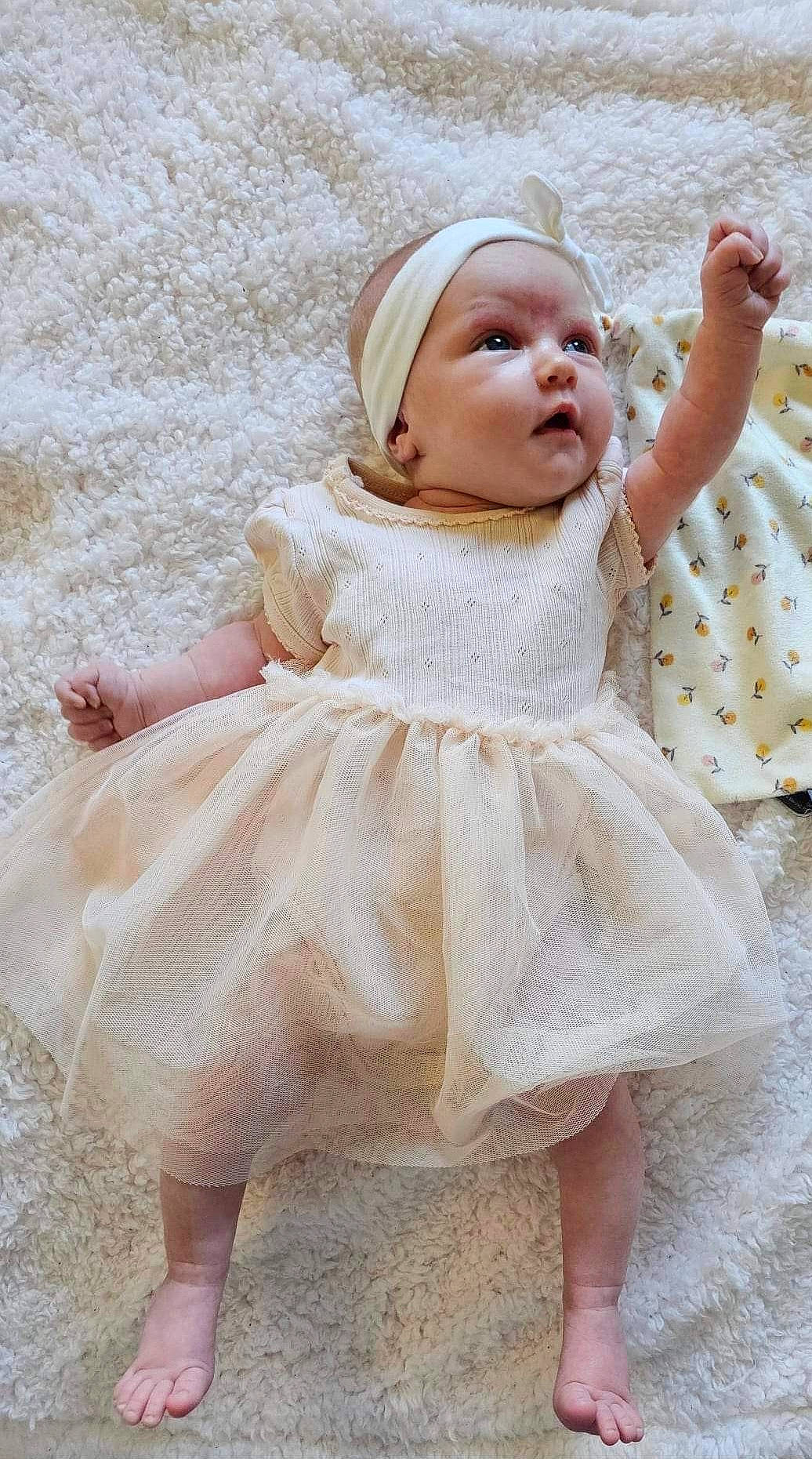 Tessa participe au concours pour gagner de l'argent avec cette photo : arm, baby, baby_toddler_clothing, comfort, day_dress, dress, embellishment, face, fashion_accessory, fur, hand, happy, headgear, pattern, peach, person, pink, skin, sleeve, toddler