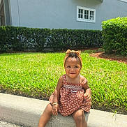 E'Nyla is registered to the contest to win money with this photo: child, toddler, smiling, dress, headband, sandals, grass, curb, outdoor, sunlight, hedge, happy, sitting, person, nature, footwear, accessory, greenery, daytime, casual