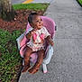 toddler, child, pink_chair, boots, sidewalk, grass, tree, outdoor, smiling, waving, jewelry, bracelets, necklace, fringed_shirt, brown_boots, short_hair, happy, person, daylight, cute