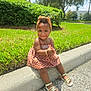 toddler, child, smiling, dress, headband, outdoor, grass, curb, sandals, sunny, nature, greenery, tree, sidewalk, playful, young_child, person, casual, daytime, happy