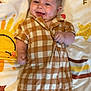 baby, infant, smiling, romper, checkered_pattern, blanket, sun, star, heart, lying_down, cute, happy, child, indoor, skin, face, hand, foot, clothing, playful