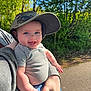 baby, child, smiling, cap, camo, outdoor, nature, trees, sunlight, person, holding, happy, face, blue_eyes, shirt, short_sleeve, jeans, hand, adult, path