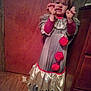 cabinet, child, clown_costume, costume, curtain, door, dress, fun, gray, indoor, long_sleeves, person, playful, pom_poms, pose, red, room, smile, wooden_floor, young