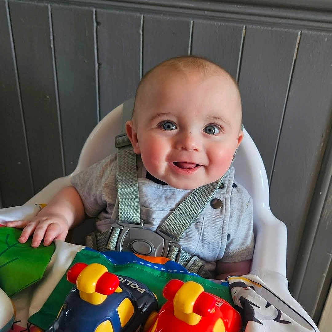 Jaxon is registered to the contest to win money with this photo: accessories, baby, babylaughing, chair, clothing, face, furniture, happy, head, jewelry, necklace, person, photography, plant, portrait, pottedplant, sitting, smile, t_shirt, toy