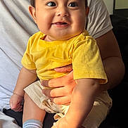 Danny joined the competition — help win amazing prizes! baby, child, infant, smiling, happy, portrait, indoor, sitting, yellow_shirt, shorts, socks, adult, parent, arms, closeup, face, eyes, family, home, photography