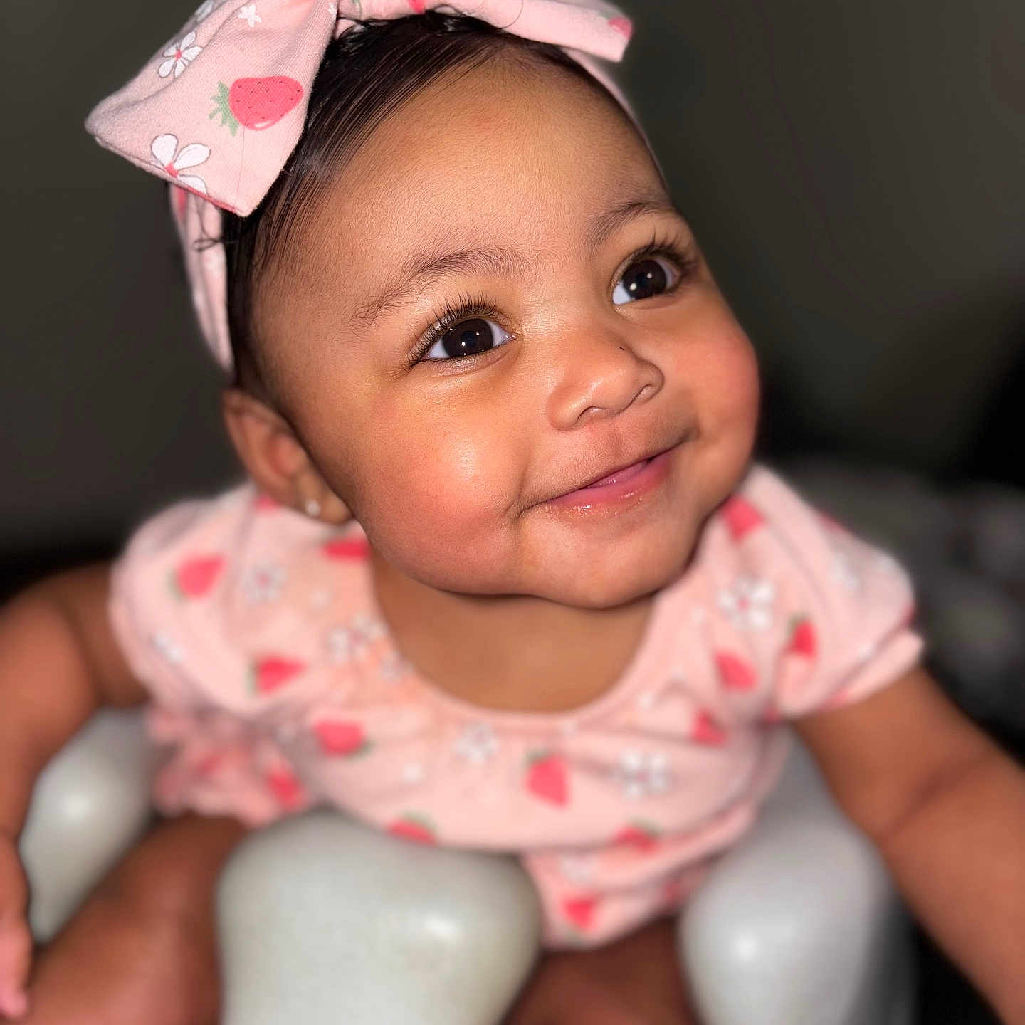Xylani is registered to the contest to win money with this photo: apparel, baby, baby_seat, cheeks, child, closeup, cute, eyes, fashion, happy, headband, indoors, infant, person, pink_clothing, portrait, seat, skin, smiling, strawberry_pattern