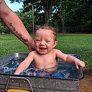 Jaxxon is registered to the contest to win money with this photo: baby, child, toddler, water, metal_tub, outdoor, grass, tree, smiling, happy, person, arm, tattoo, splashing, summer, nature, playful, cute, skin, daylight