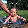 baby, child, toddler, water, metal_tub, outdoor, grass, tree, smiling, happy, person, arm, tattoo, splashing, summer, nature, playful, cute, skin, daylight
