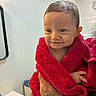 baby, towel, wet_hair, smile, tattoo, hand, bracelet, bathroom, sink, mirror, person, child, cute, expression, indoor, red, skin, holding, portrait, young