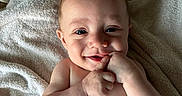 Jaxxon is registered to the contest to win money with this photo: baby, infant, smile, face, hand, skin, towel, lying_down, cute, happy, child, portrait, young, person, baby_skin, indoors, expression, human, resting, closeup