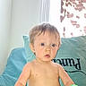 toddler, child, indoor, couch, pillow, curtain, toy, blue_eyes, shirtless, light, window, hair, face, expression, young_child, home, furniture, sitting, curious, bright
