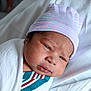 newborn, baby, infant, hospital, blanket, cap, face, person, bed, swaddled, closeup, skin, headwear, cute, lying_down, indoors, sleepwear, portrait, young, resting
