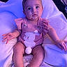 baby, infant, child, pink_outfit, headband, bunny_design, blanket, soft_texture, indoor, seated, cute, portrait, looking_at_camera, wide_eyes, chubby_arms, chubby_legs, footwear, baby_boy, baby_girl, expression