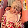 baby, child, smiling, pink, hat, bib, car_seat, floral_pattern, knitted, pom_pom, cute, infant, clothing, portrait, happy, seated, indoors, soft_lighting, closeup, person