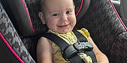 Trinity is registered to the contest to win money with this photo: baby, child, car_seat, graco, smile, yellow, flower, hair_accessories, seatbelt, window, car_interior, safety, infant, cute, happy, portrait, seat, clothing, hands, road_trip