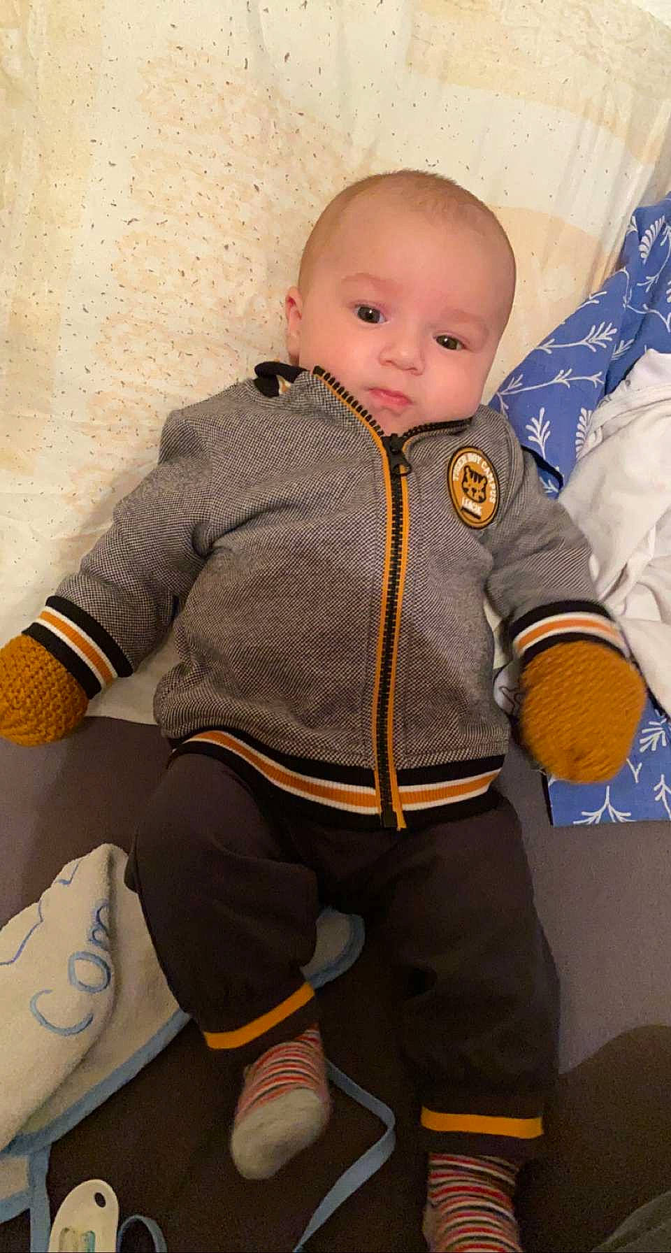 Léo participe au concours pour gagner de l'argent avec cette photo : baby, baby_products, baby_toddler_clothing, button, carmine, cheek, child, collar, flooring, jacket, knee, outerwear, pattern, person, personal_protective_equipment, sitting, sleeve, textile, toddler, wood