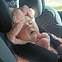 baby, car_seat, child, child_seat, cozy, cute, fuzzy, headwear, infant, nap, outdoor_light, peaceful, pink_clothing, portrait, relaxation, seatbelt, sleeping, soft_texture, straps, sunlight