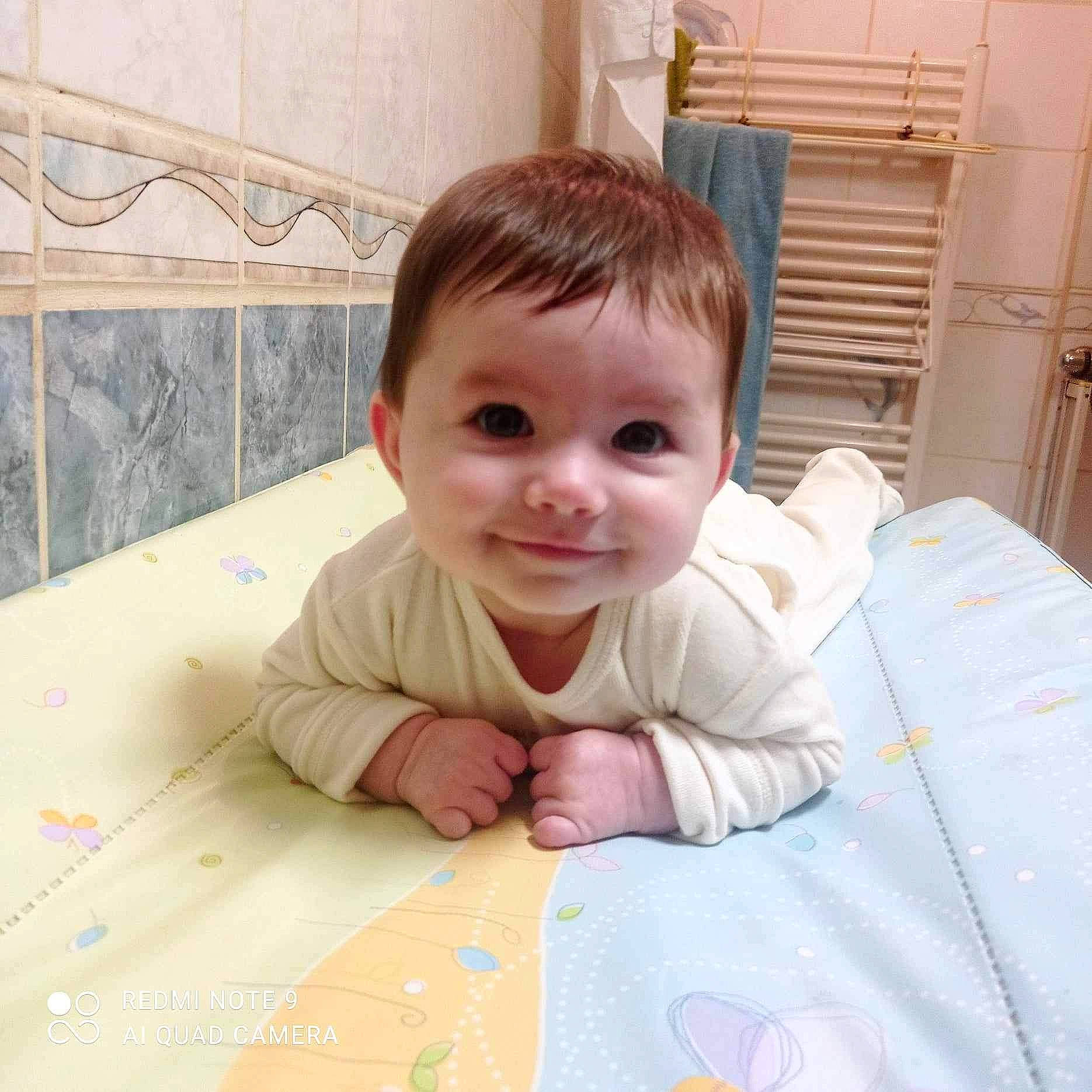 Salomé a rejoint le concours — aidez-le/la à gagner de superbes lots ! baby, baby_toddler_clothing, cheek, child, eye, finger, floor, flooring, happy, hardwood, head, iris, joy, linens, nose, pattern, person, skin, smile, toddler