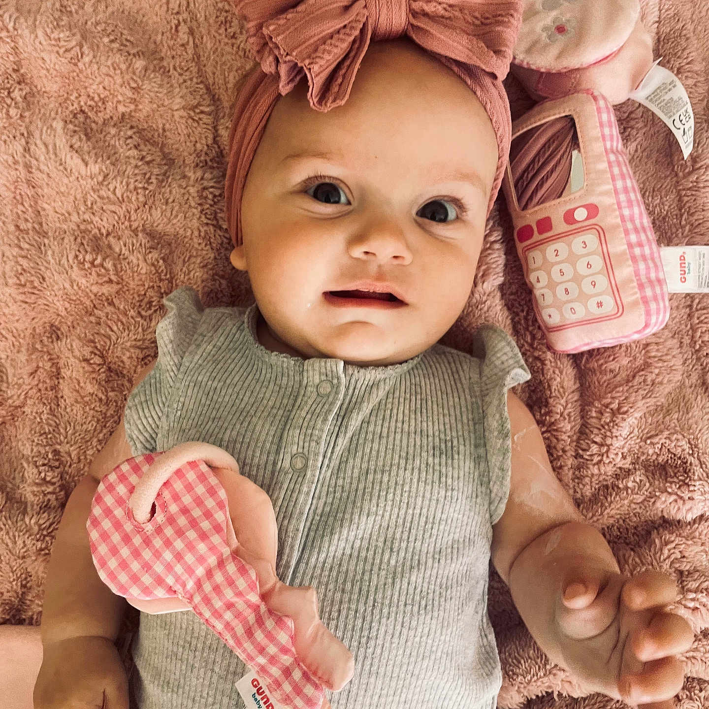 Sophie is registered to the contest to win money with this photo: accessories, baby, biting, bodypart, clothing, face, finger, hand, happy, hat, head, headband, newborn, person, photography, portrait, sitting, smile, spitting, toy