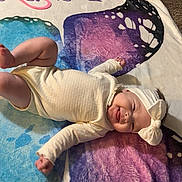 Emersyn joined the competition — help win amazing prizes! baby, infant, blanket, butterfly, headband, tongue_out, playful, indoors, carpet, toy, colorful, child, smiling, cute, lying_down, clothing, floor, person, happy, young
