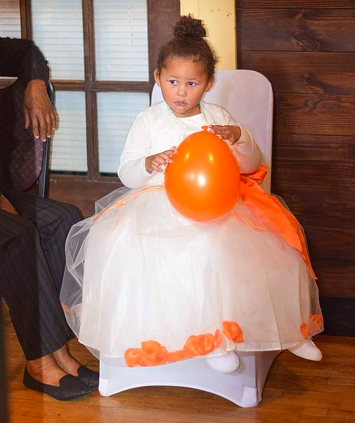 Kaidynce is registered to the contest to win money with this photo: ball, balloon, child, comfort, event, flooring, formal_wear, fun, hairstyle, happy, hardwood, orange, party_supply, peach, person, room, sandal, shoulder, sitting, toddler