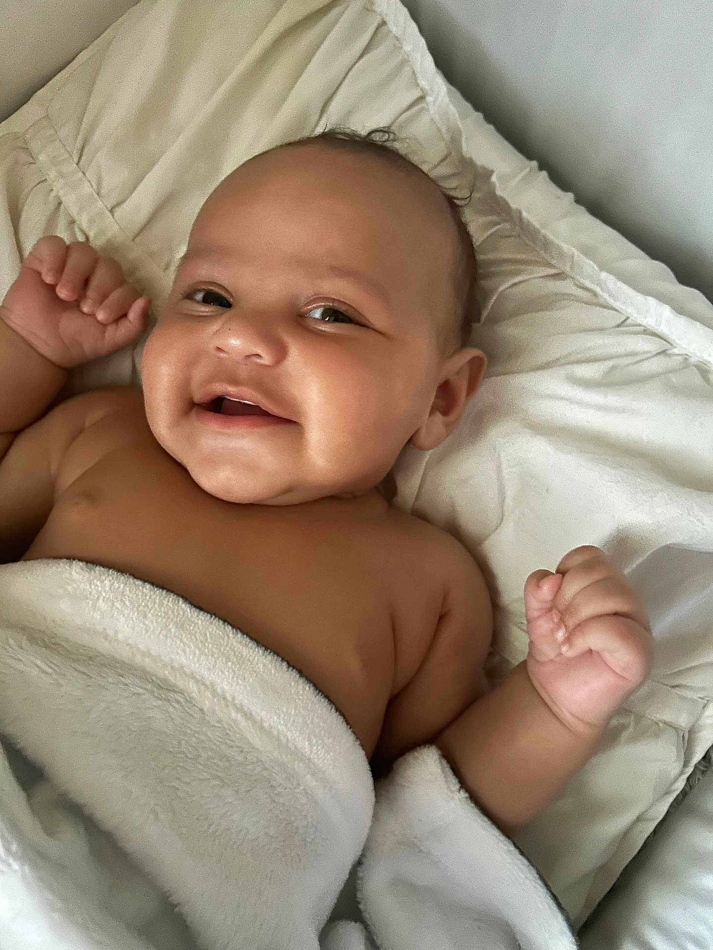 Binyamyin is registered to the contest to win money with this photo: baby, smiling, blanket, bed, infant, face, skin, cheeks, hand, comfort, lying_down, cute, happy, child, soft, cozy, indoors, portrait, young, expression