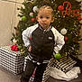 Shiza is registered to the contest to win money with this photo: child, girl, christmas_tree, ornaments, presents, holiday, festive, black_jacket, boots, posing, indoor, flooring, decorations, lights, hair_bow, smiling, winter_clothing, celebration, young_child, cute