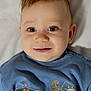 baby, infant, child, face, portrait, blue_shirt, cute, smile, eyes, hair, lying_down, soft_light, indoor, closeup, toddler, clothing, expression, skin, head, person