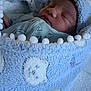 newborn, baby, sleeping, blanket, blue, pom_poms, cozy, soft, face, infant, wrapped, cute, child, indoors, peaceful, rest, comfort, warm, portrait, close_up