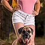 Fera participe au concours pour gagner de l'argent avec cette photo : woman, dog, outdoor, grass, pink_top, white_shorts, harness, summer, portrait, pet, animal, nature, confident, standing, sitting, happy, sunlight, casual, footwear, tattoo