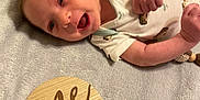 Johnathon is registered to the contest to win money with this photo: baby, infant, one_month, smiling, lying_down, blanket, onesie, cute, milestone, wooden_sign, face, skin, hand, head, newborn, happy, portrait, closeup, indoors, soft_texture