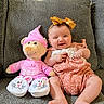 Blessie Rosalie is registered to the contest to win money with this photo: baby, bow, smile, plush_toy, teddy_bear, pink_clothing, romper, couch, gray_couch, indoor, child, cute, happy, sitting, footwear, bunny_slippers, headband, toy, infant, cozy
